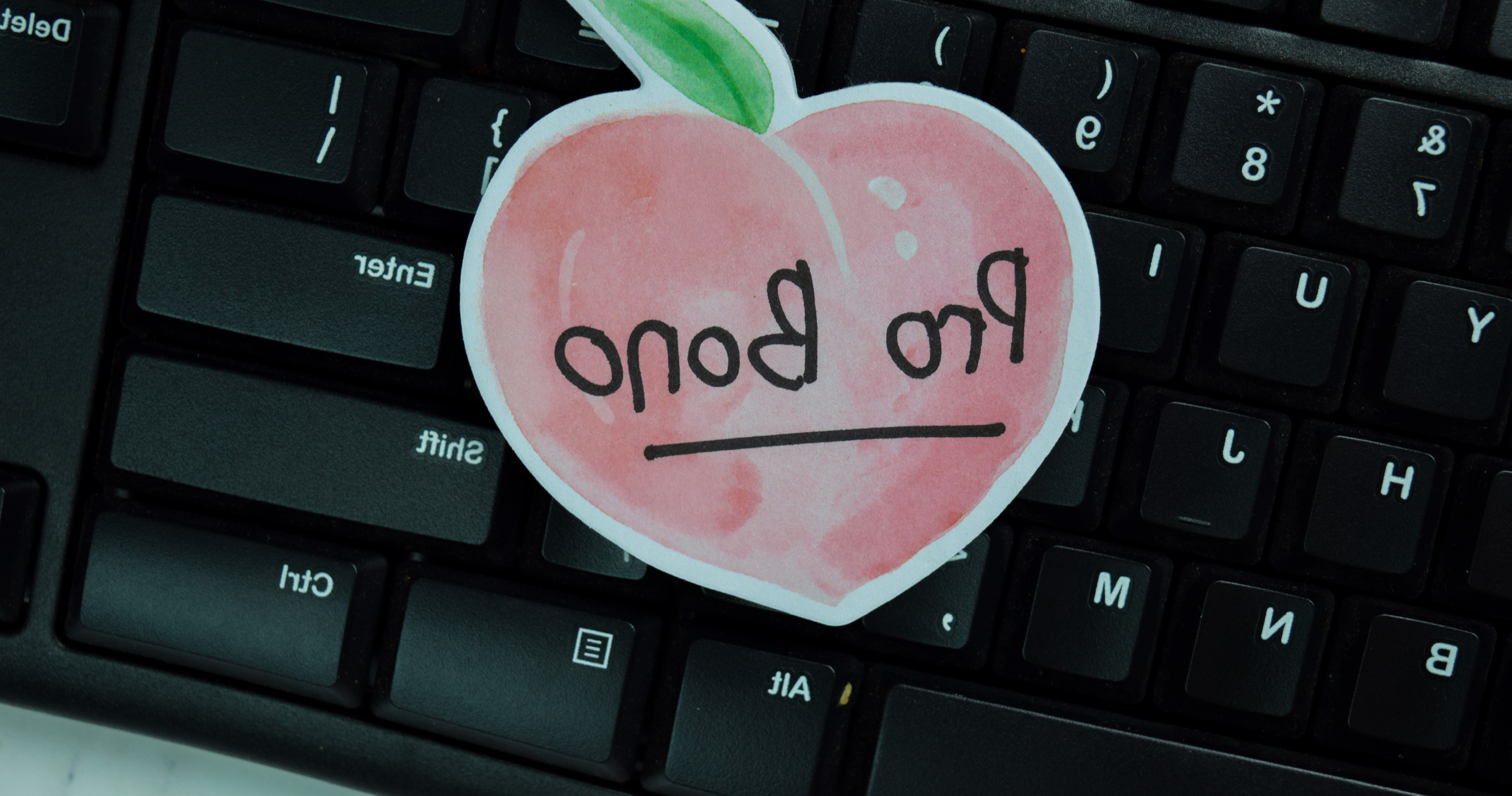 Hand drawn peach that reads 'Pro Bono' on a black computer keyboard